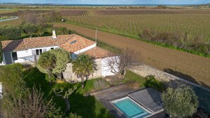 Una villa con tetto in tegole, piscina e vista su campi coltivati.