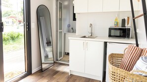 A compact kitchen with white cabinets, a microwave, and a wicker basket with pillows.