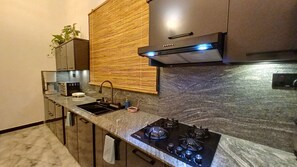 A modern kitchen with a gas stove, a sink, and a built-in oven. - Elegant Resort Hiriketiya (Dikwella)