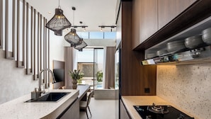 Une cuisine moderne dotée d’un comptoir incurv é, d’une cuisinière intégrée, de luminaires suspendus et offrant une vue sur l’espace extérieur.