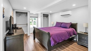 A bedroom with a bed, bedside tables, a wardrobe, and an air conditioning unit.