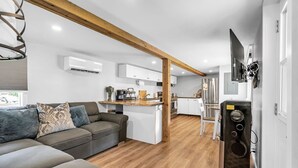 A modern living room with a sofa, a coffee table, and a kitchen area with cabinets and a refrigerator.