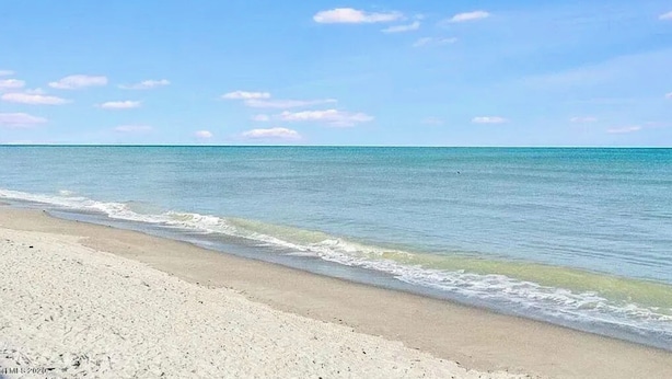 Una playa con aguas azules cristalinas y una orilla arenosa.