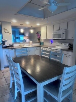 Una cocina moderna con una isla central, muebles blancos y un ventilador de techo.