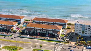 Un hotel frente al mar con varias construcciones, estacionamientos y vistas a la playa.