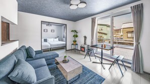 A modern living room with a sofa, coffee table, and a view of a balcony. - HILLS NISEKO 105 (Niseko)