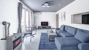 A modern living room with a grey sofa, a coffee table, and a TV displaying 'NETFLIX'. - HILLS NISEKO 105 (Niseko)
