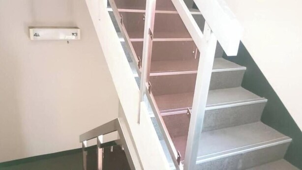 A staircase with a handrail and a light switch on the wall. - HotelSumi (Naha)