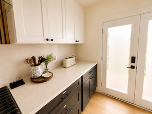 A kitchen with white cabinets, a toaster, and a plant on the counter. - Muse Atelier | Midtown Houston (Houston)