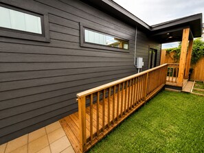 Une maison moderne dotée d’une terrasse en bois et d’un petit jardin.