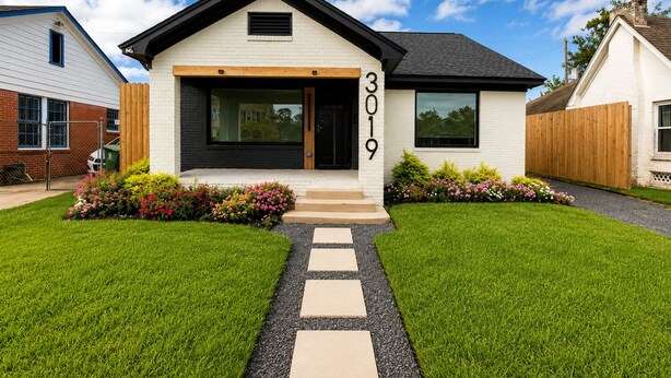 A modern two-story house with a black front door, number 3019, and a well-maintained lawn with stepping stones leading to the entrance. - Muse Atelier | Midtown Houston (Houston)