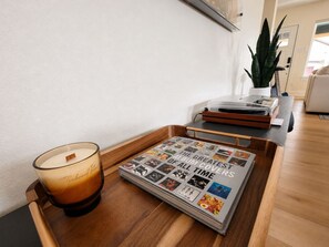 A tray with a candle and a magazine on a wooden surface. - Muse Atelier | Midtown Houston (Houston)
