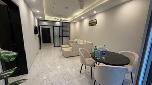 Moderni hotellihuone, jossa on ruokailutila, sohvaryhmä ja kattotuuletin.