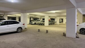 Maanalainen pysäköintihalli, jossa on useita parkkeerattuja autoja, betonipilareita ja tasainen katto, jossa on valaisin.