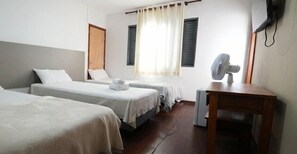 A hotel room with two single beds, a wooden desk, a chair, a fan, and a window with curtains. - Thermas da Mantiqueira Poços de Caldas (Poços de Caldas)