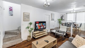 A living room with a TV, a coffee table, a sofa, and a dining area with chairs and a table. - Heart of DT Alhambra Walk to Starbucks Near DTLA A (Alhambra)