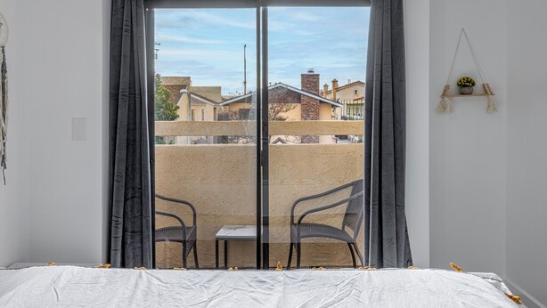 A room with a sliding glass door leading to an outdoor balcony with two chairs and a small table. - Heart of DT Alhambra Walk to Starbucks Near DTLA A (Alhambra)
