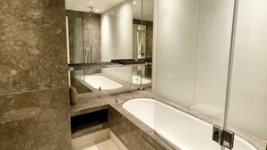 A modern bathroom with a glass-enclosed shower, a freestanding bathtub, and a vanity with a mirror. - Luxury Canary Wharf 1 bed apt (London)
