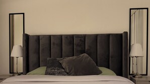 A neatly made bed with a dark headboard, two bedside lamps, and a mirror on each side. - Luxury Canary Wharf 1 bed apt (London)