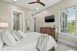 A bedroom with a bed, a dresser, a television, and a window with blinds. - Indigeaux in Blue Mountain Beach: Spacious 4BR home with lake views - 6 Seater LSV (Santa Rosa Beach)