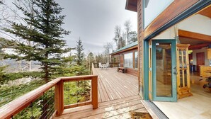 Eine Holzterrasse mit Geländer, mit Blick auf ein bewaldetes Gebiet.