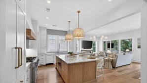 A modern kitchen with white cabinetry, a wooden island, and pendant lighting. - BRAND NEW BUILD; Gorgeous home with POOL, Hot Tub, and steps to BEACH! (Isle Of Palms)