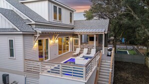 A two-story house with a covered patio, a pool, and a deck with lounge chairs. - BRAND NEW BUILD; Gorgeous home with POOL, Hot Tub, and steps to BEACH! (Isle Of Palms)