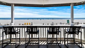 Et overdækket udendørs siddeområde med udsigt til stranden.
