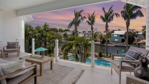 Ein geräumiger Balkon mit Blick auf einen Pool, Palmen und einen Sonnenuntergang.