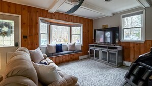 A cozy living room with a built-in bench, a large TV, and a fireplace. - Cozy Private Home | Near DC & Military Bases (Indian Head)