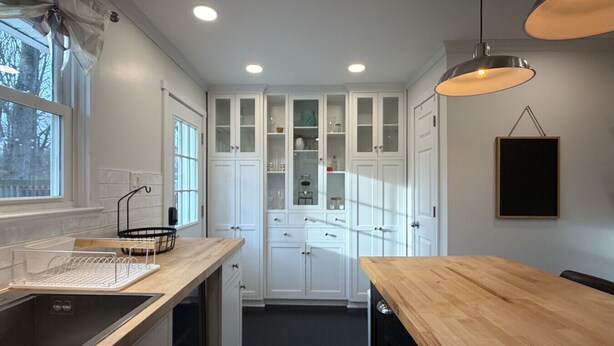 A modern kitchen with white cabinets, a wooden countertop, and a hanging pendant light. - Cozy Private Home | Near DC & Military Bases (Indian Head)