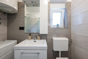 Un baño moderno con lavamanos, espejo y retrete blancos.
