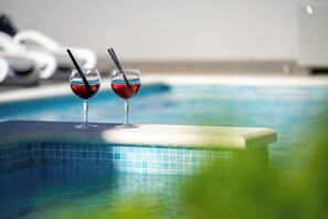 Una piscina con dos vasos de líquido rojo en el borde.