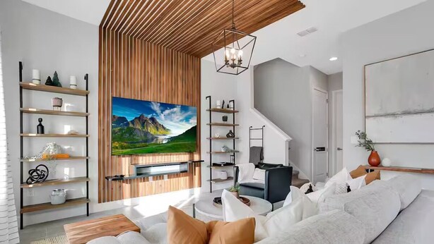 Ein modernes Wohnzimmer mit großem Flachbildfernseher, Holzregalen, einer Couch und einem Couchtisch.