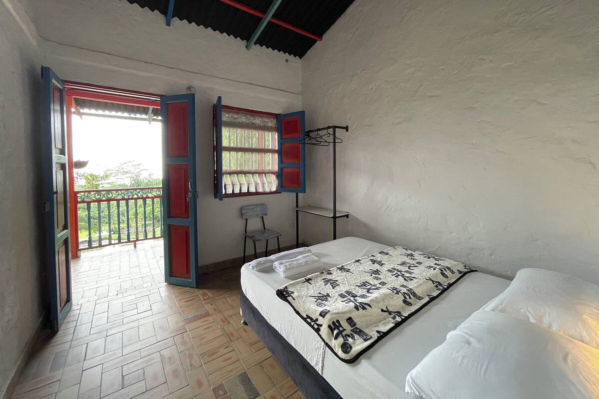 A bedroom with a bed, a window with a view, and a door leading to an outdoor area.