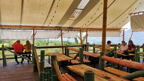 An outdoor dining area with bamboo furniture and a canopy overhead. - Aldea Los Pioneros (Venecia)