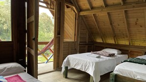 A wooden cabin with two beds, a hammock, and a view of the outdoors. - Aldea Los Pioneros (Venecia)