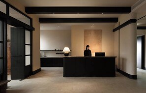 A reception area with a receptionist, a counter, a lamp, and a kitchen in the background. - Joyee Sky City Hotel Chongqing-Jiefangbei (Chongqing)