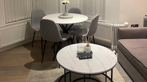 Ett hörnrum med ett matbord, stolar, ett litet runt bord med ljus, ett element och en soffa.