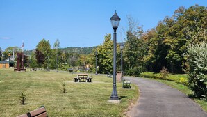 A park with a paved path, benches, and a lamp post. - Cozy 2-bedroom house in Haines Falls near Katterskill falls . (Haines Falls)