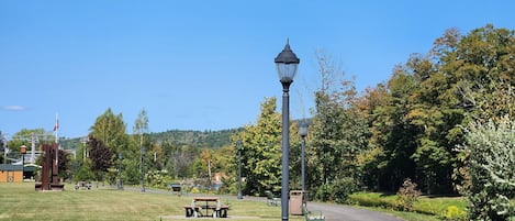 A park with a paved path, benches, and a lamp post.