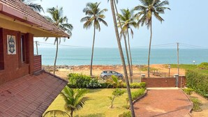 A coastal property with a paved driveway, palm trees, and a view of the sea. - Lahari by Hireavilla - Chic 4BR Beachfront Villa (Udupi)