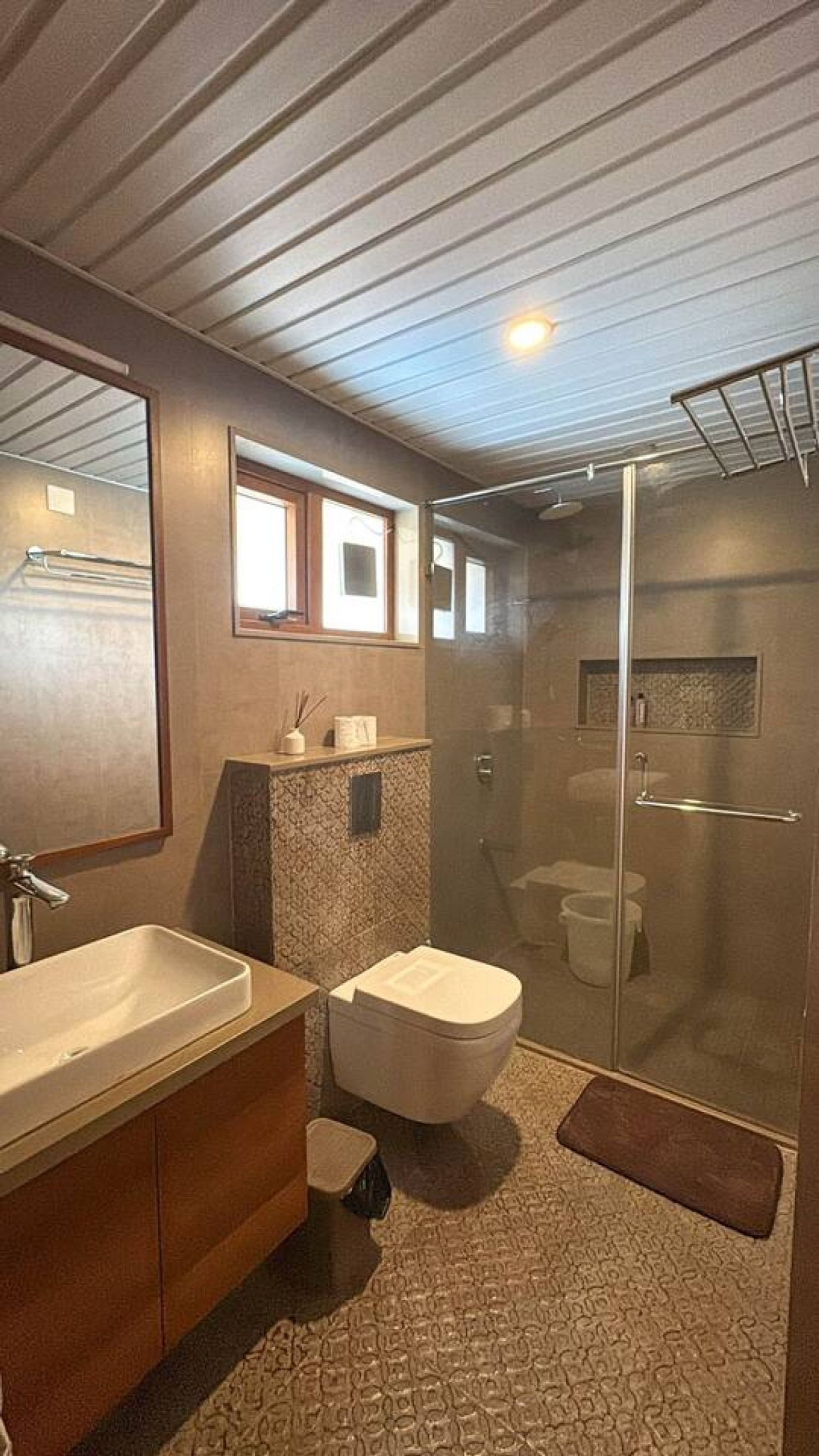 Un baño moderno con un espejo grande, un lavabo, un inodoro y una zona de ducha.