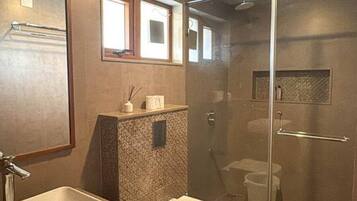 Un baño moderno con un espejo grande, un lavabo, un inodoro y una zona de ducha.
