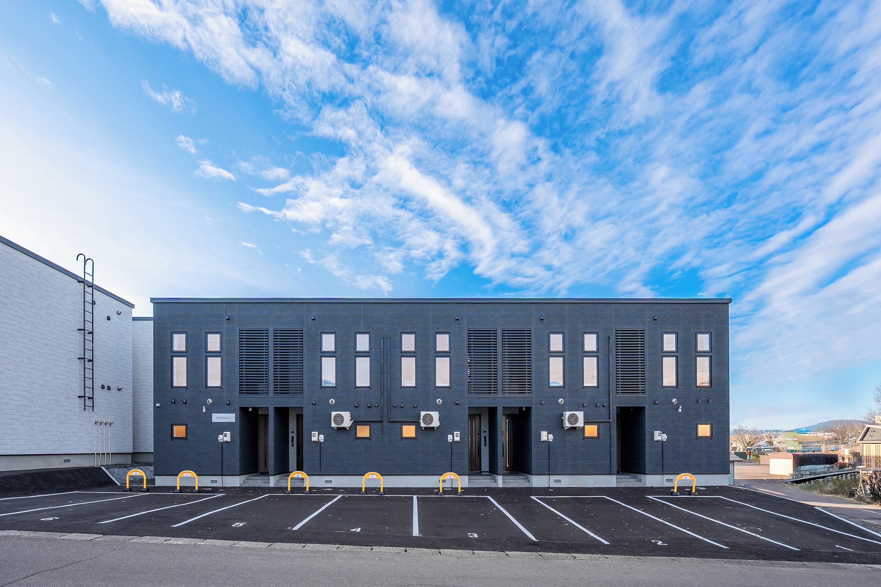 A modern building with a parking lot in front.