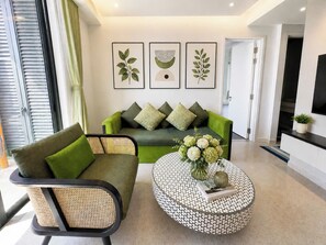 A modern living room with a green sofa, a round coffee table, and framed artwork on the wall. - Minerva Apartment - Fireworks View, Sunset Town Phu Quoc (An Thoi)