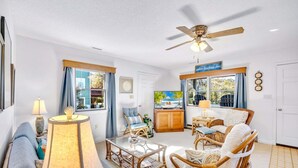 A cozy living room with wicker furniture, a ceiling fan, and a TV. - Canalfront, Cozy 3BR with Amazing sound views! (Frisco)
