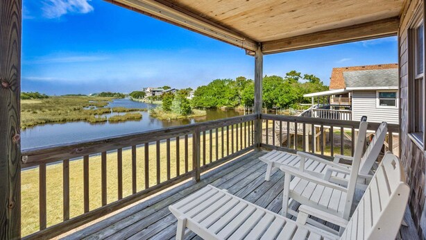 A wooden deck with white chairs overlooking a body of water and a house. - Canalfront, Cozy 3BR with Amazing sound views! (Frisco)