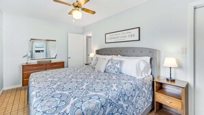 A bedroom with a bed, a nightstand, a lamp, a ceiling fan, a mirror, and a framed sign on the wall. - Canalfront, Cozy 3BR with Amazing sound views! (Frisco)