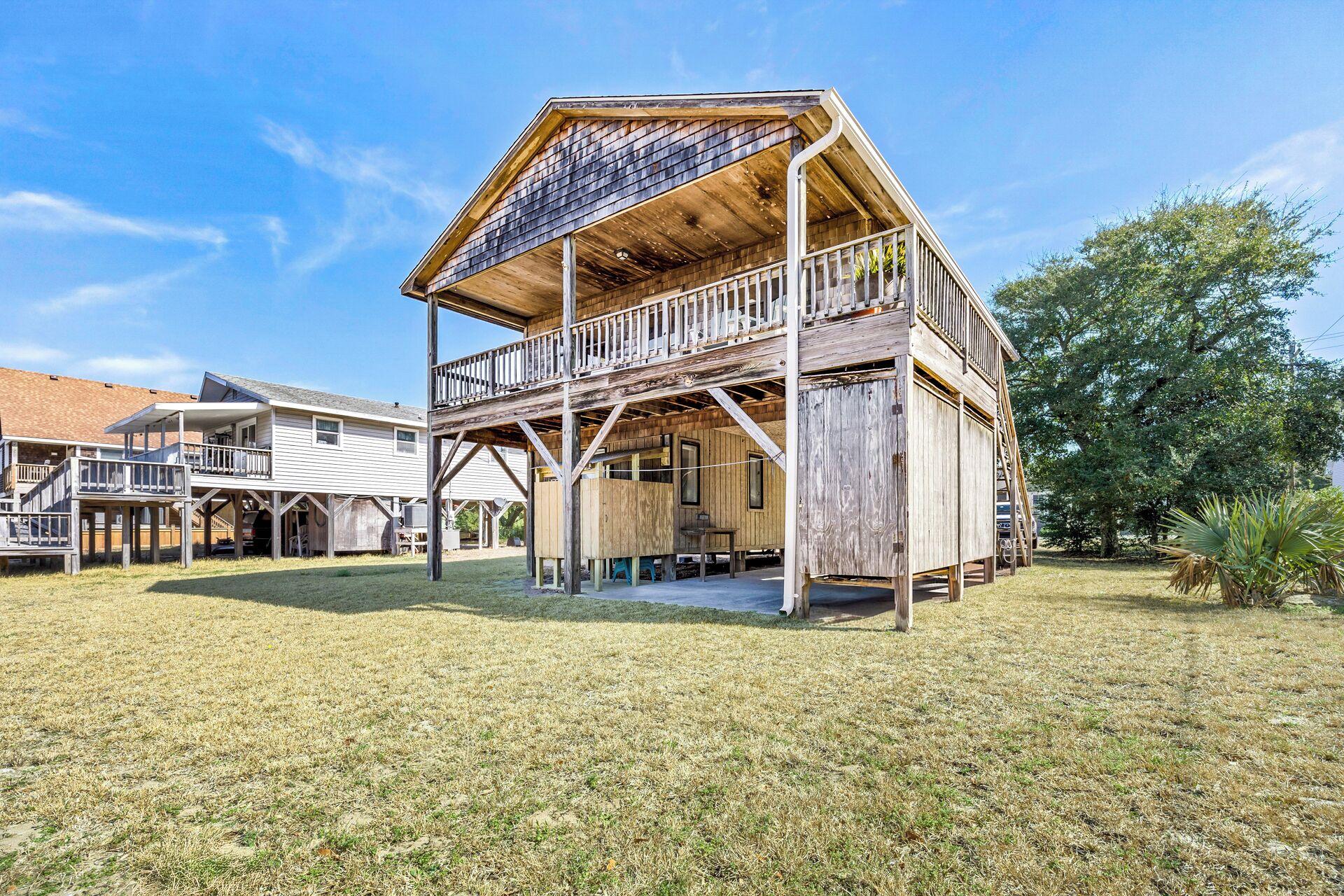 A wooden cabin with a balcony, a covered porch, and a small deck area.